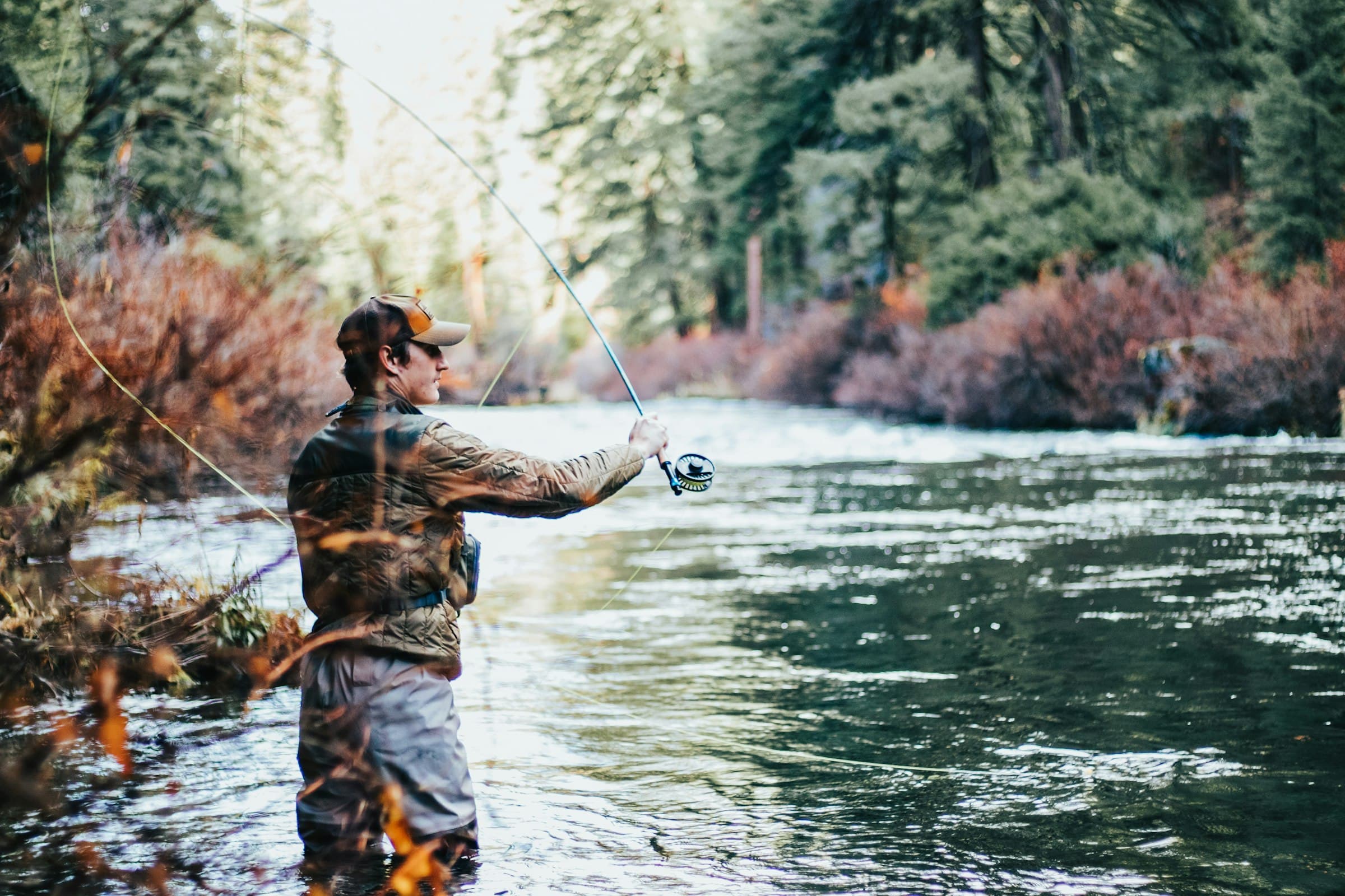 Angler casting a fly rod while wading in a river